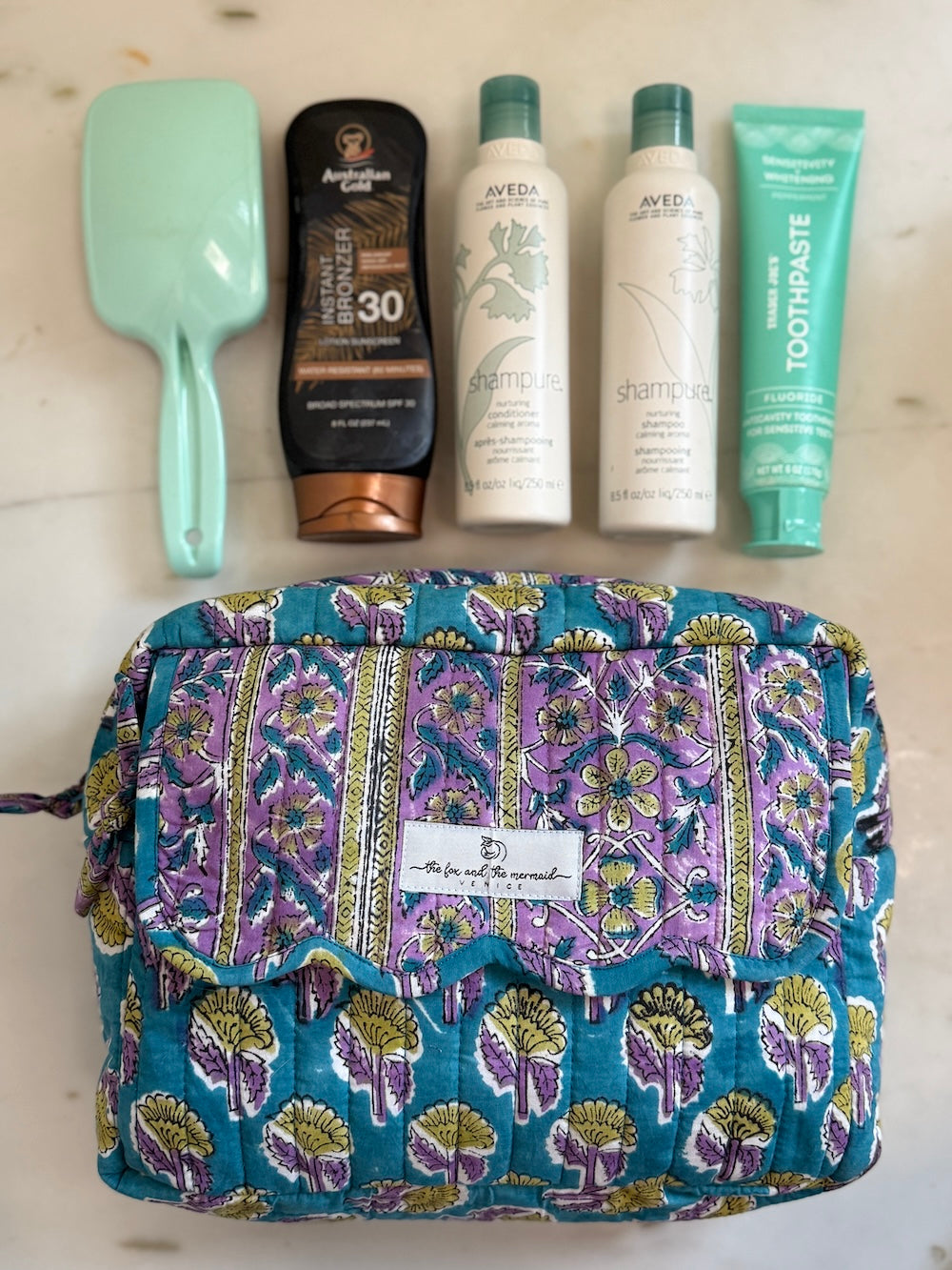 blue and lavender block print cosmetic bag set shown with full-size shampoo and toiletries for scale